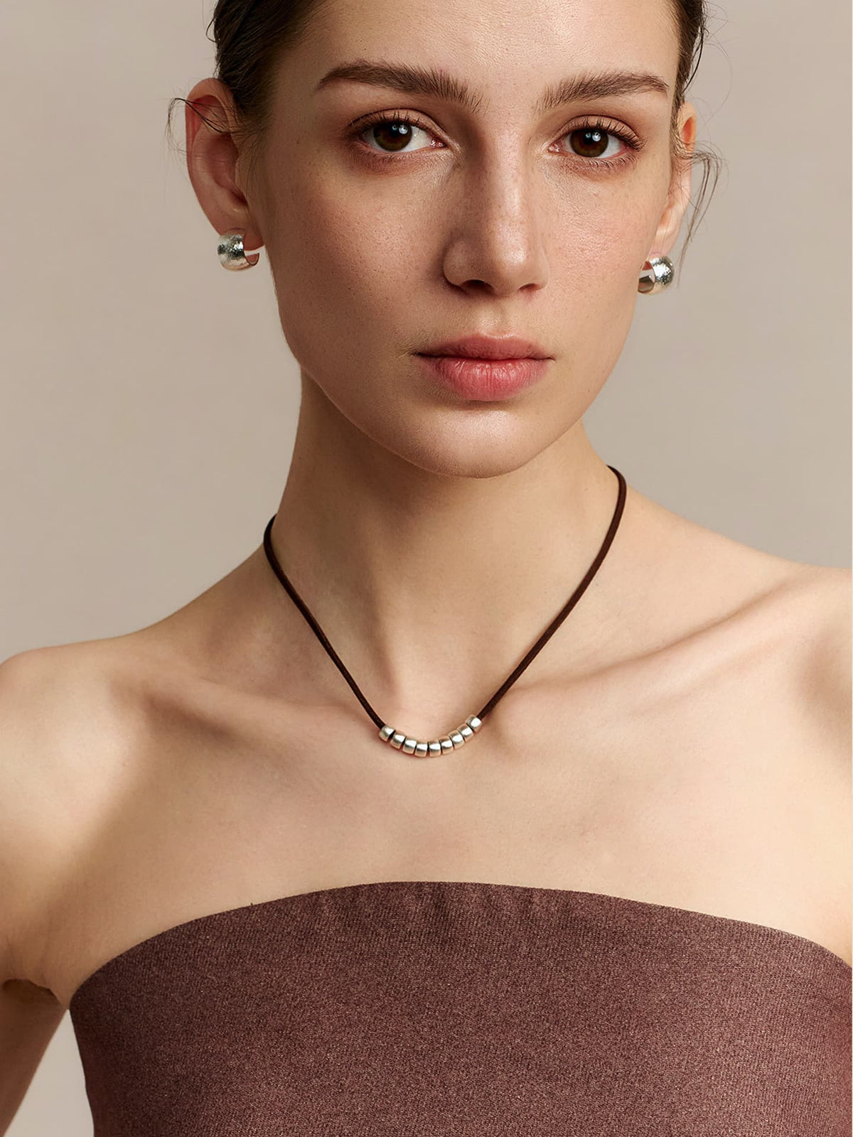 A model wearing Fairyokai Balance Glide leather and silver bead necklace, facing the camera, on a neutral background.
