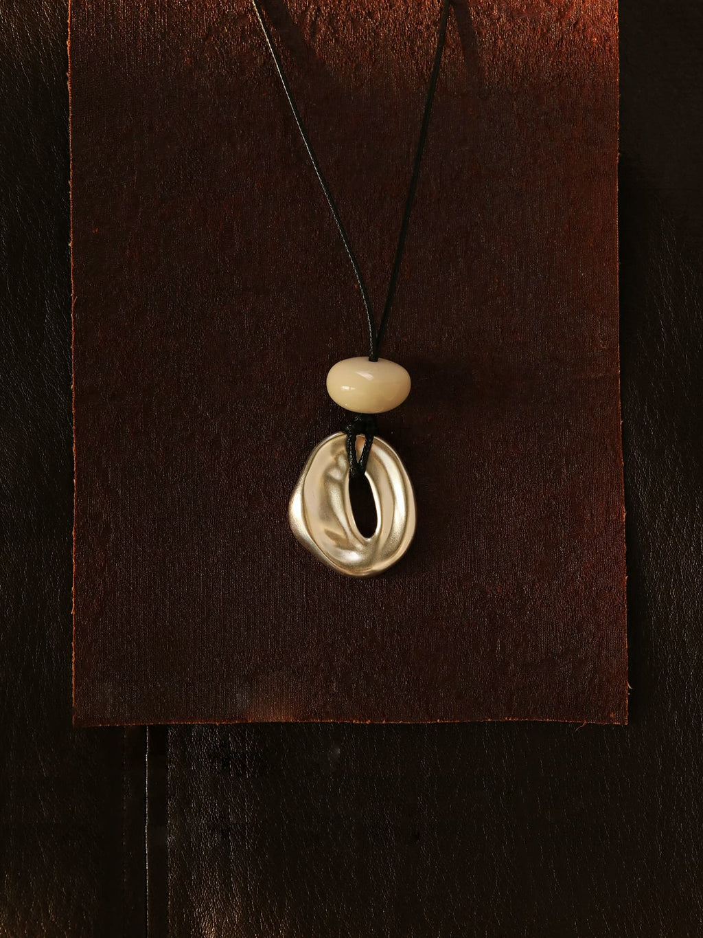 Fairyokai Breath Pendant adjustable waxed cord oval necklace suspended against a brown background.