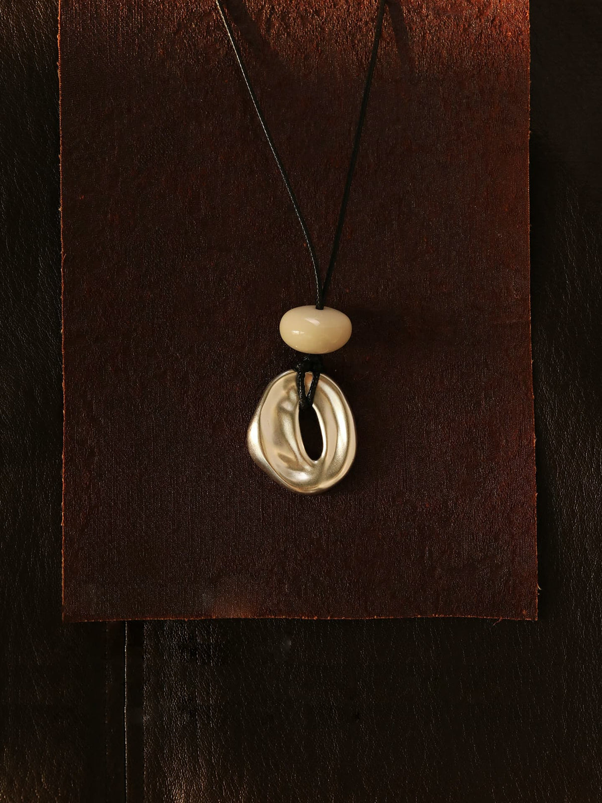Fairyokai Breath Pendant adjustable waxed cord oval necklace suspended against a brown background.
