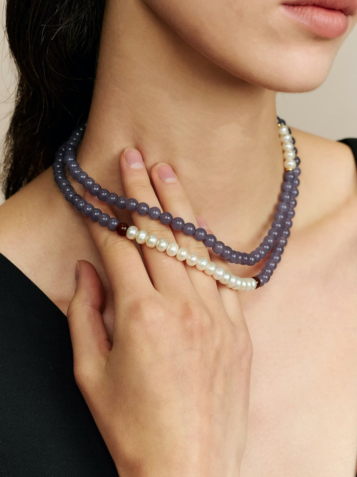Close-up of a model wearing Fairyokai Chrysoprase and Pearl double-layer necklace wrapped twice around the neck, with her hand gently touching the necklace.