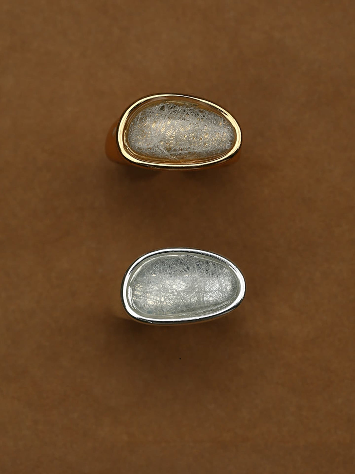 Fairyokai Crack Light resin gold ring flat-laid on a brown background, shown in gold-tone and silver-tone versions.