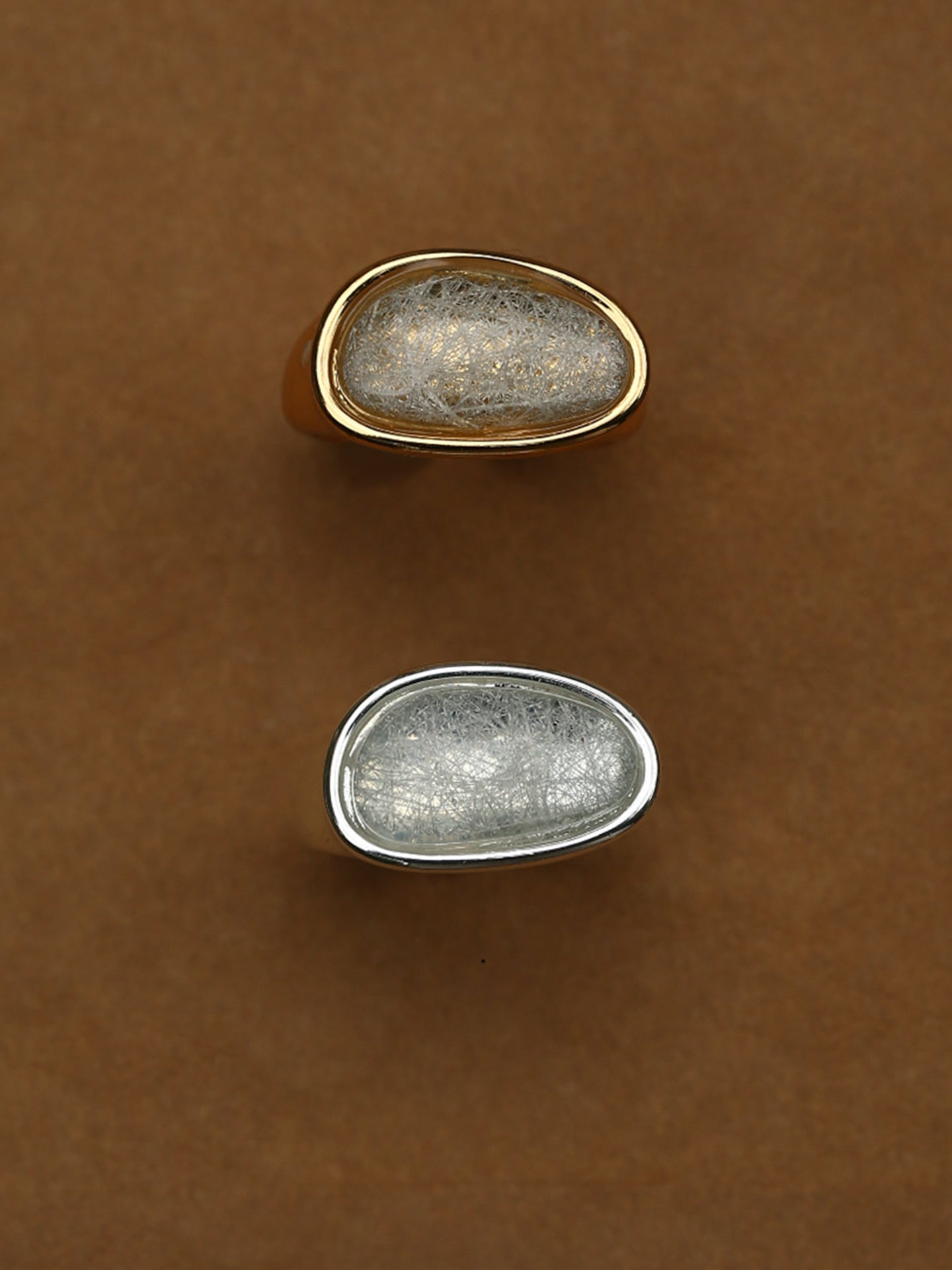 Fairyokai Crack Light resin gold ring flat-laid on a brown background, shown in gold-tone and silver-tone versions.