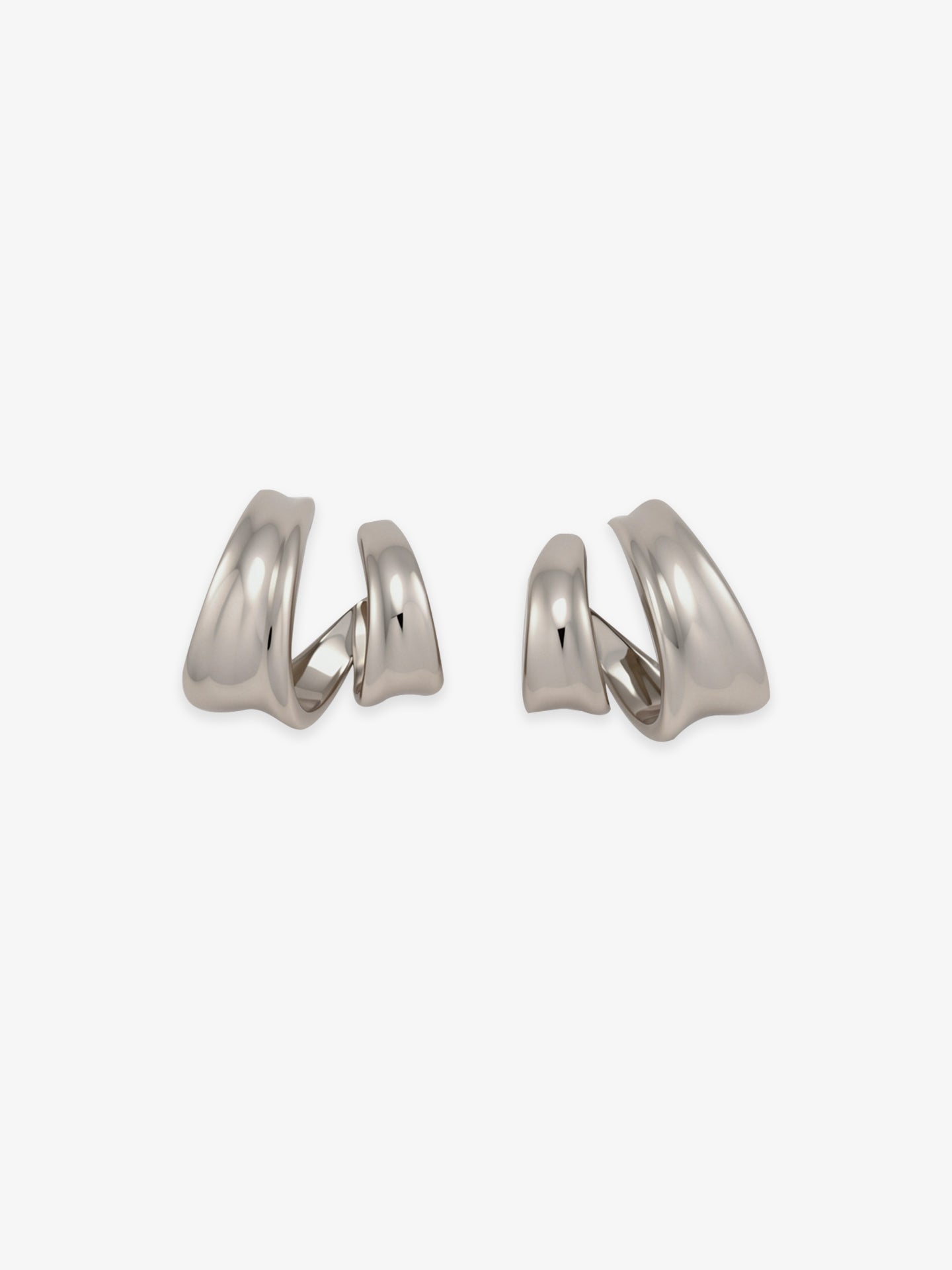 Pair of Fairyokai Double Arc sculptural open C-shape hoop earrings with white gold tone plating on white background.