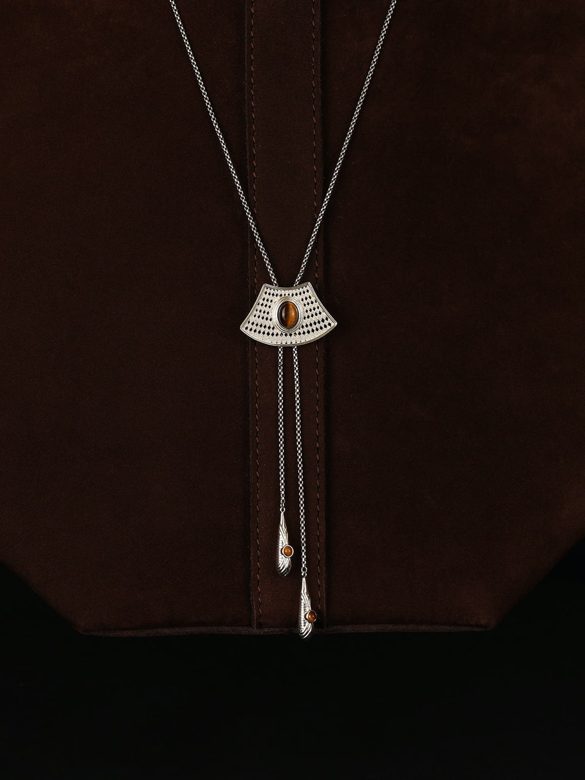 Fairyokai Flowing River adjustable tiger eye fan necklace draped over a dark brown bag, front close-up view.