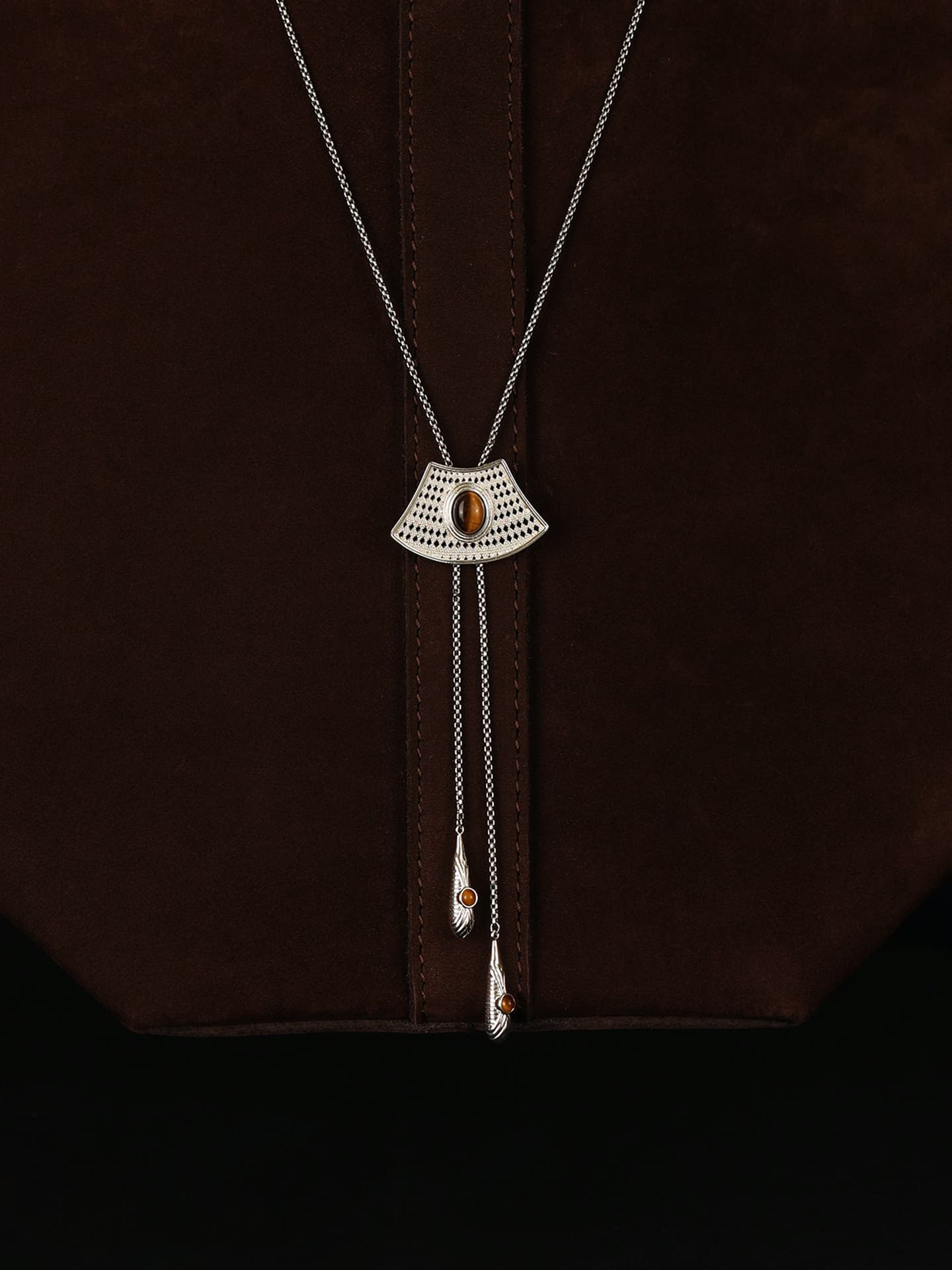Fairyokai Flowing River adjustable tiger eye fan necklace draped over a dark brown bag, front close-up view.
