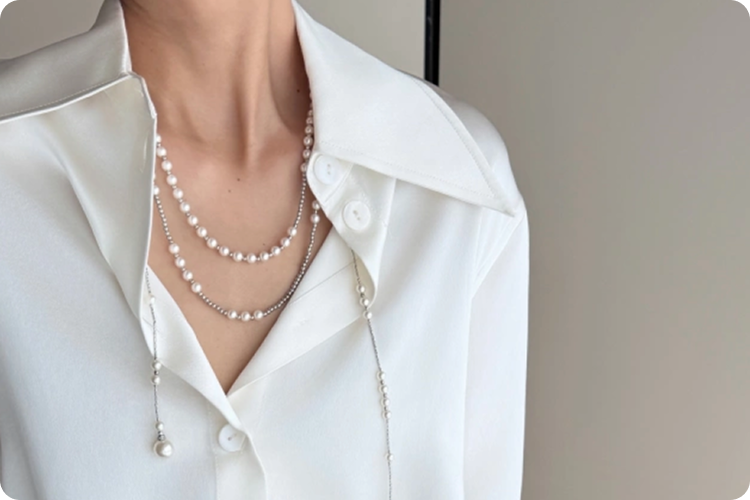 A woman in a white shirt, wearing a Fairyokai Layered Adjustable Double-Layer Faux Pearl Necklace, close-up on her neck and the white shirt.