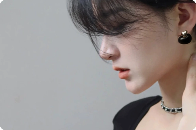 A woman wearing Fairyokai Tranquil Ebony Stream Stone Earrings, close-up on her left face and the earrings, side profile.