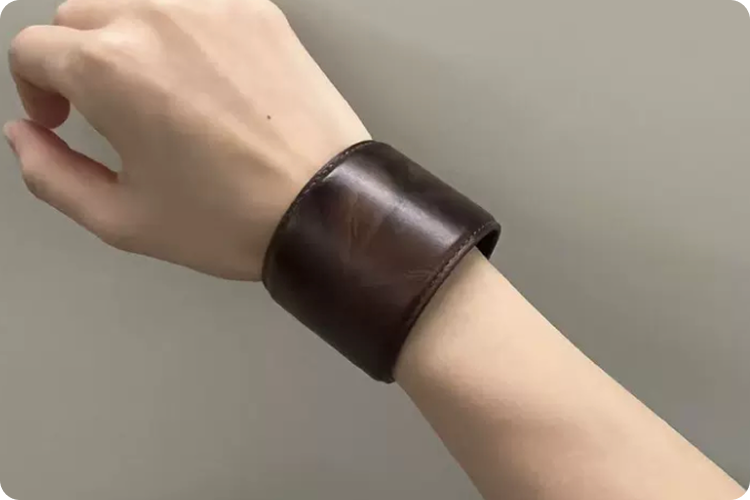 Close-up of a hand wearing a Fairyokai Vein Cuff PU Leather Set Bracelet, on light gray background.