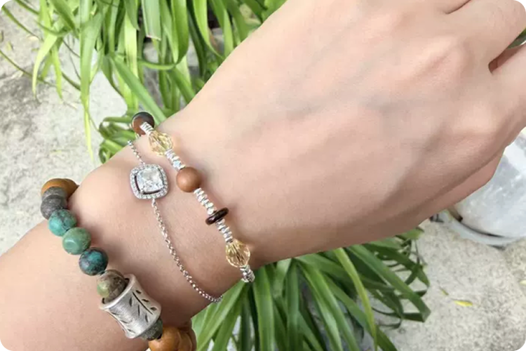 Close-up of a hand wearing a Fairyokai Soft Pure Light Mixed Stone Braided Bracelet alongside a turquoise bead bracelet.