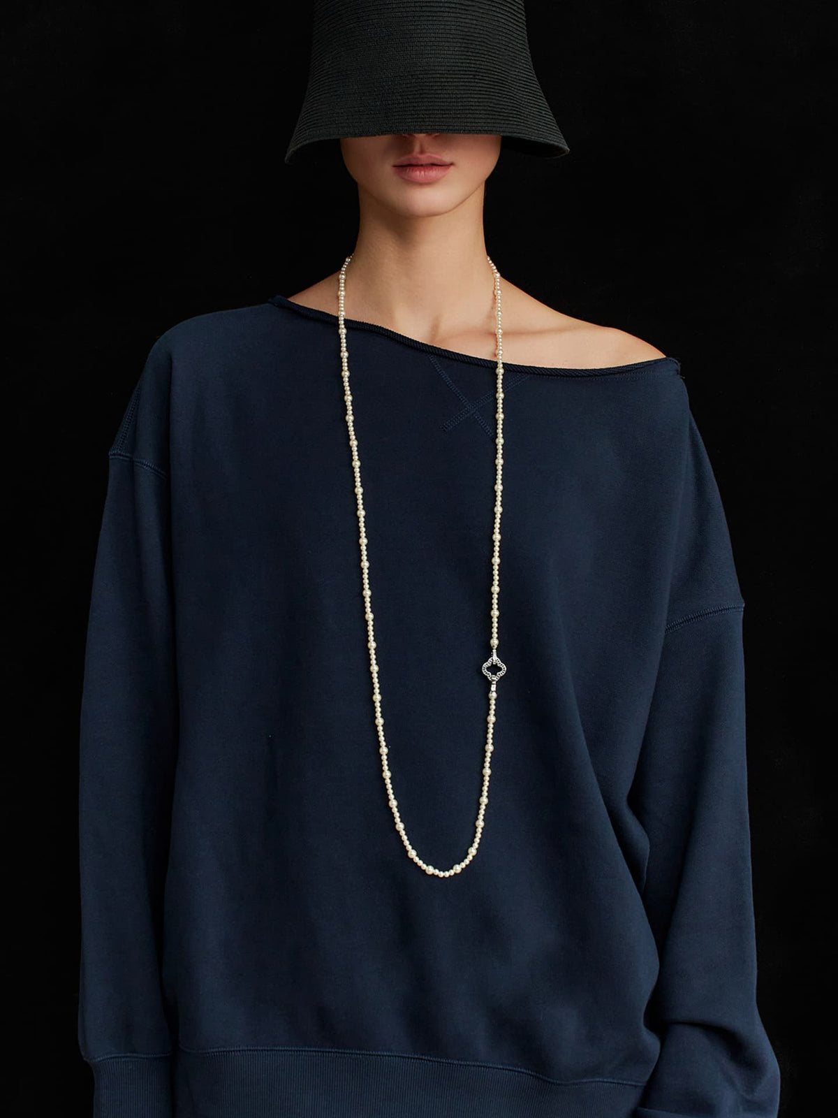 Model standing facing forward, wearing a black hat that covers her eyes and a navy top, with the Fairyokai Layered Abundance alternating faux pearl necklace around her neck.