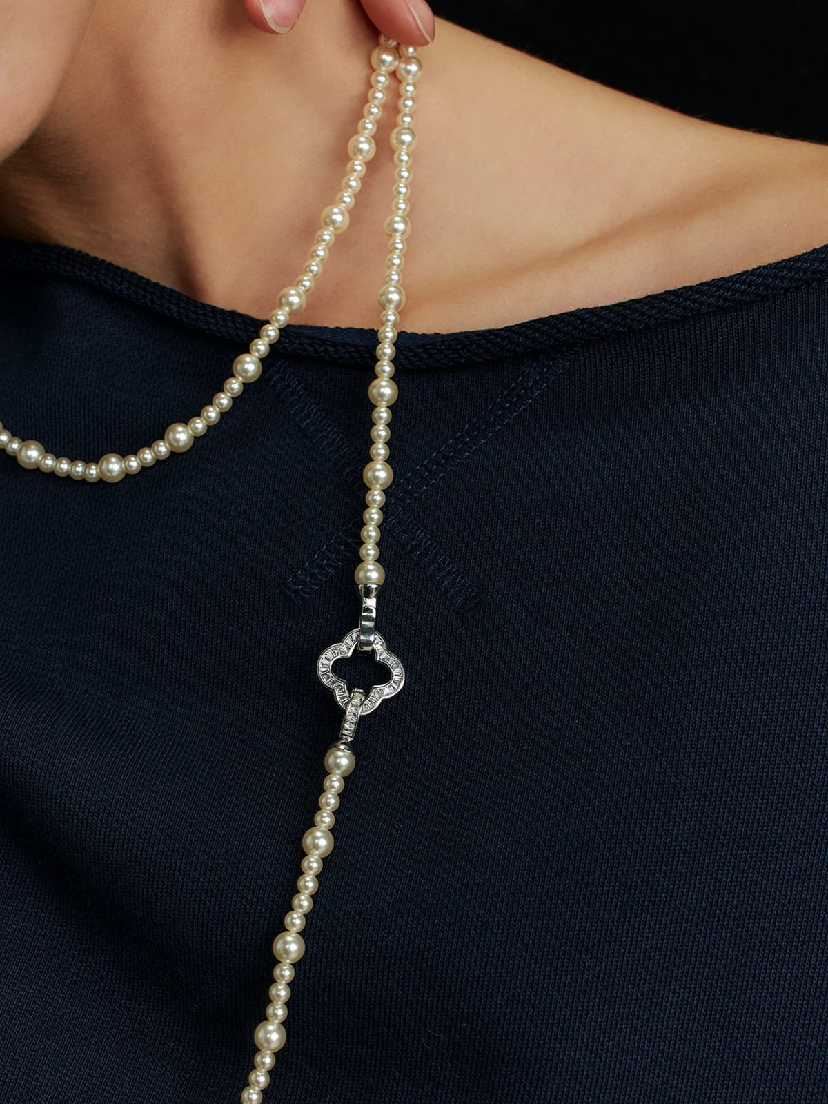 Close-up of a model's left shoulder and neck wearing a navy top, with the Fairyokai Layered Abundance alternating faux pearl necklace around her neck.