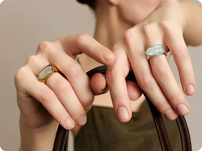 Close up of a woman wearing two Fairyokai crack light resin rings, with a bag in her hands.