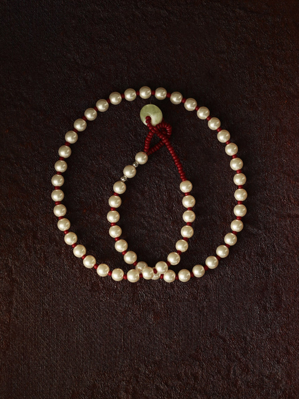 Fairyokai Lunar Chord Czech bead and jade pearl necklace (red) on a dark brown background.