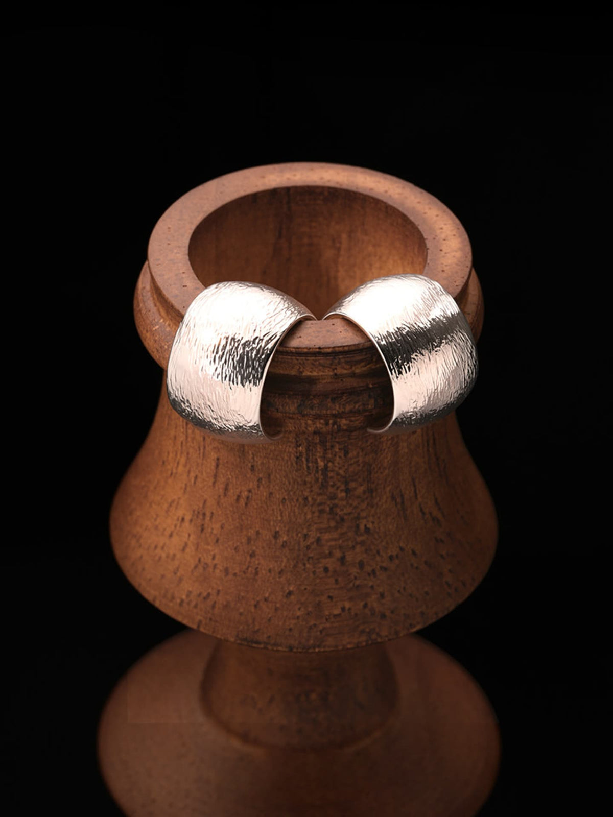 Fairyokai Moon Trace sand-textured C-shape hoop earrings hanging on a wooden display stand against a black background.