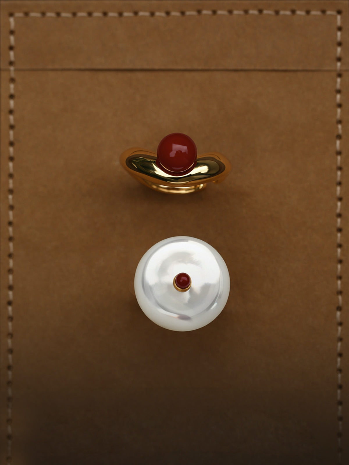 Fairyokai Ocean View mother-of-pearl and red agate open ring flat-laid on a brown leather surface, shown with the matching round shell disc detail.