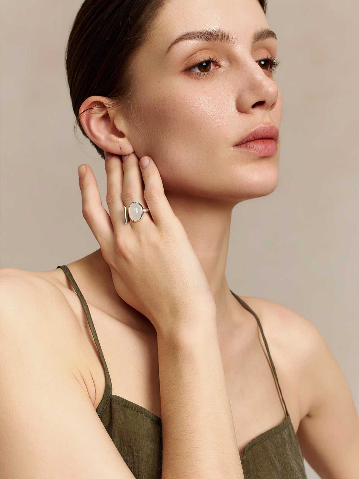 Model wearing the Fairyokai Open Chord silver natural stone ring, hand near the ear in a calm side-facing portrait.