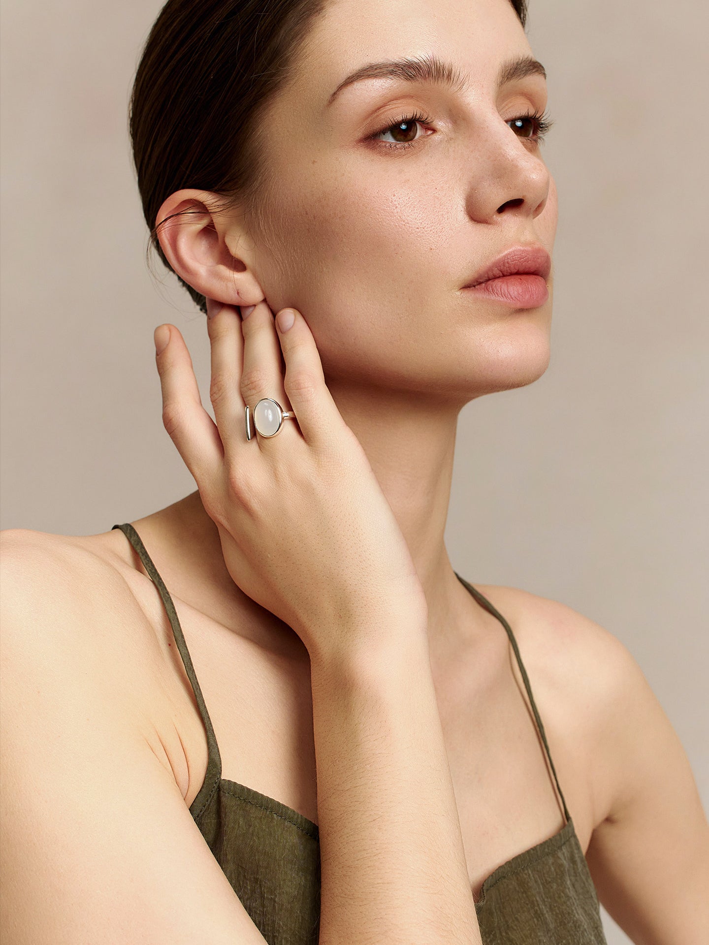 Model wearing the Fairyokai Open Chord silver natural stone ring, hand near the ear in a calm side-facing portrait.