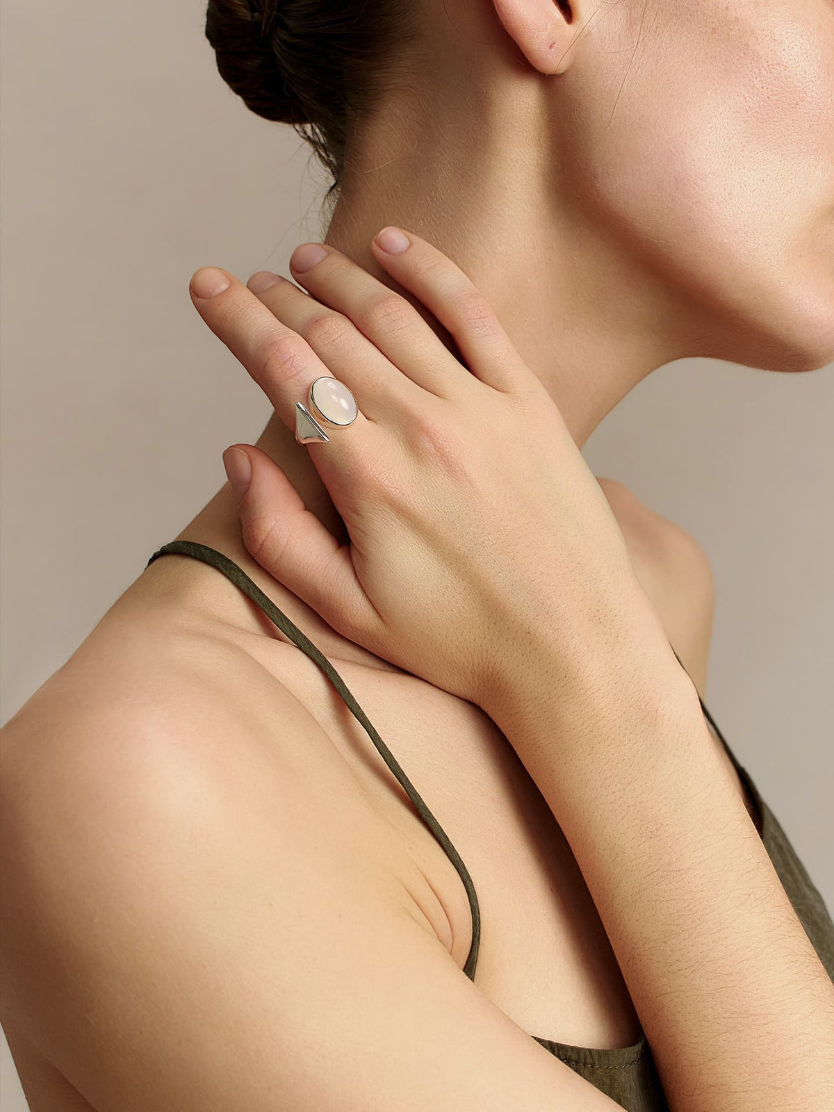 Close-up of a model wearing the Fairyokai Open Chord silver natural stone ring, hand placed near the neck and shoulder.