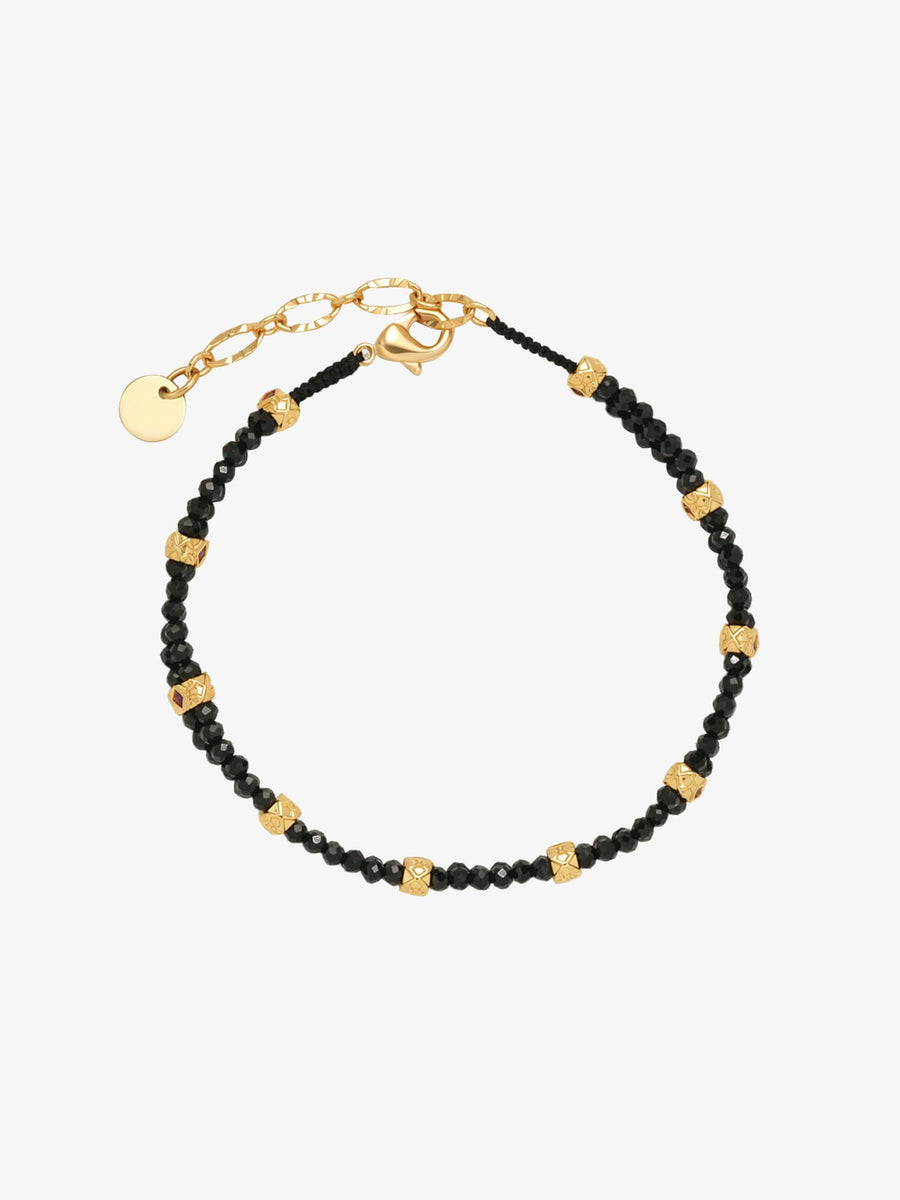 One Fairyokai Rhythm Between double-layer black spinel bracelet on a clean white background, with black beads, gold-tone accents, and adjustable cord ends.