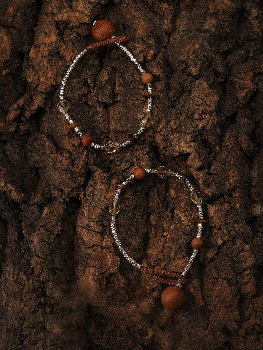 Two Fairyokai Soft Pure Light tay wood crystal braided necklaces flat lay on a wood grain background, top-down view.