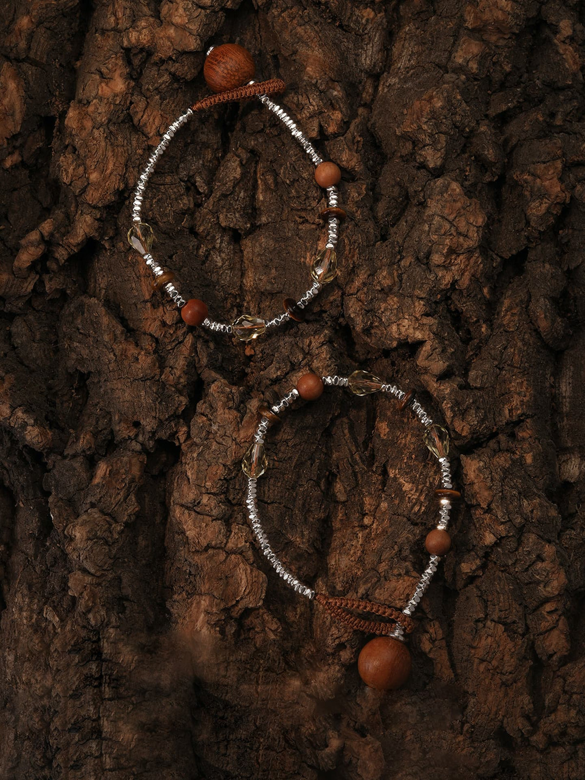 Two Fairyokai Soft Pure Light tay wood crystal braided necklaces flat lay on a wood grain background, top-down view.