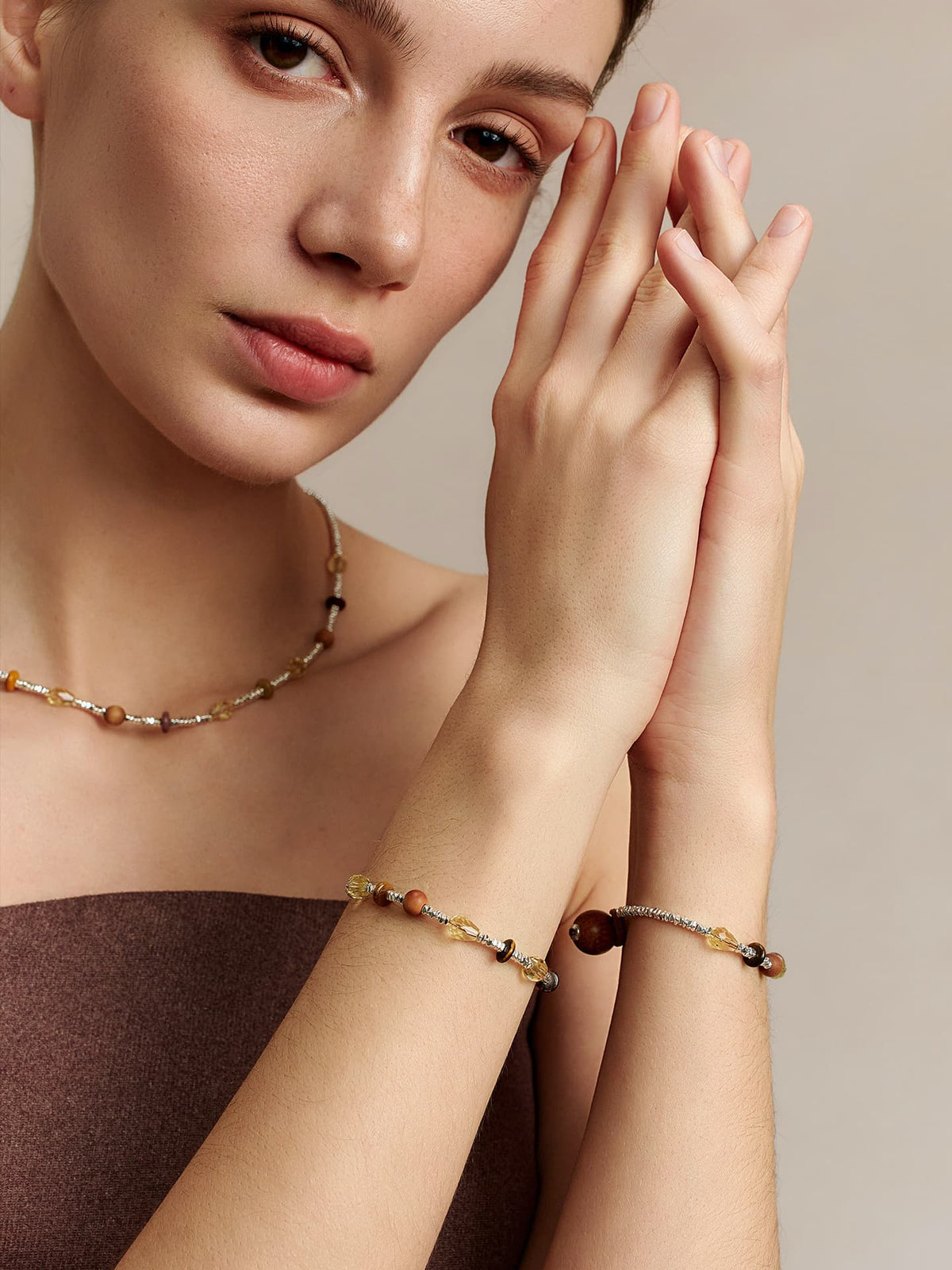 Model wearing the Fairyokai Soft Pure Light tay wood crystal braided necklace and matching bracelet, hands pressed together at her forehead, facing the camera on a white background.