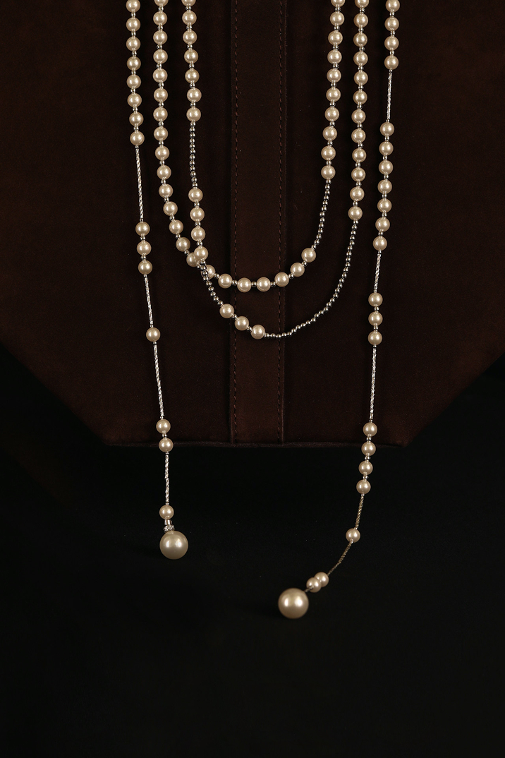 Fairyokai silver beaded necklace on a brown bag on dark background 