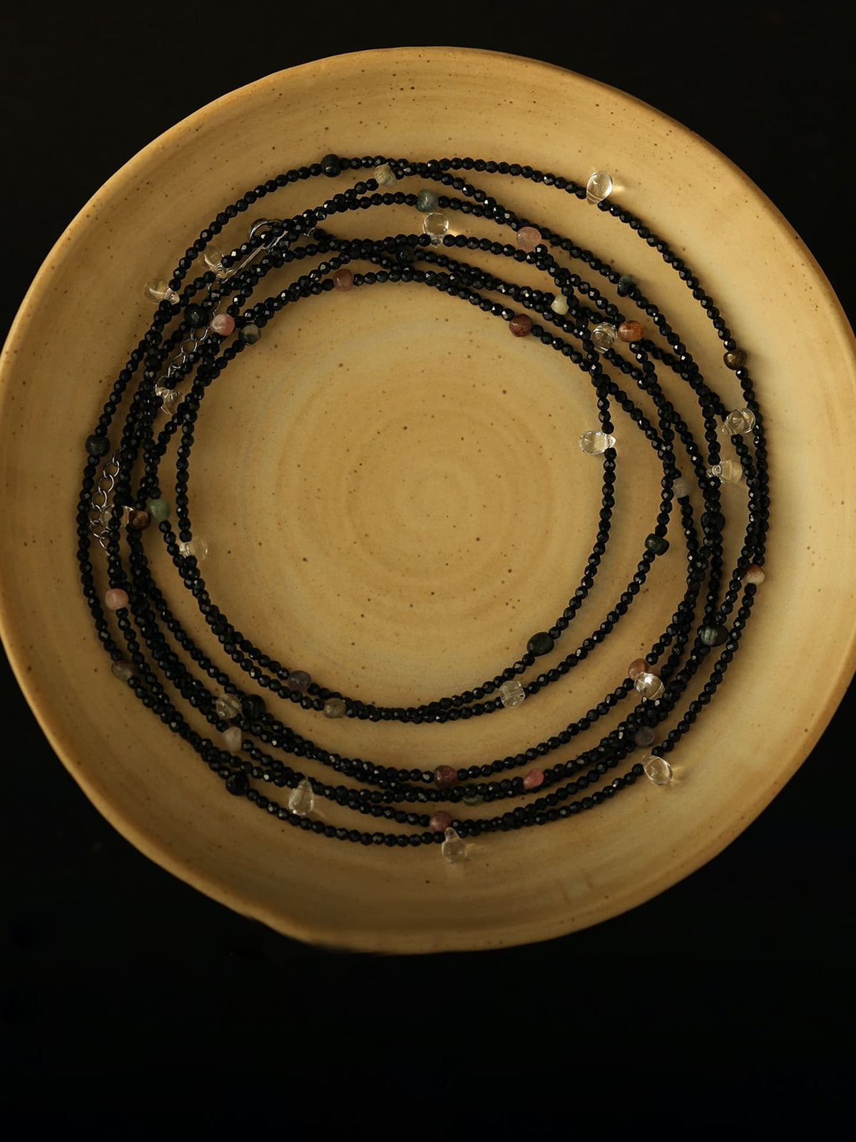 Fairyokai Starlight Chain multi-layer necklace coiled on a yellow round plate, top-down view.