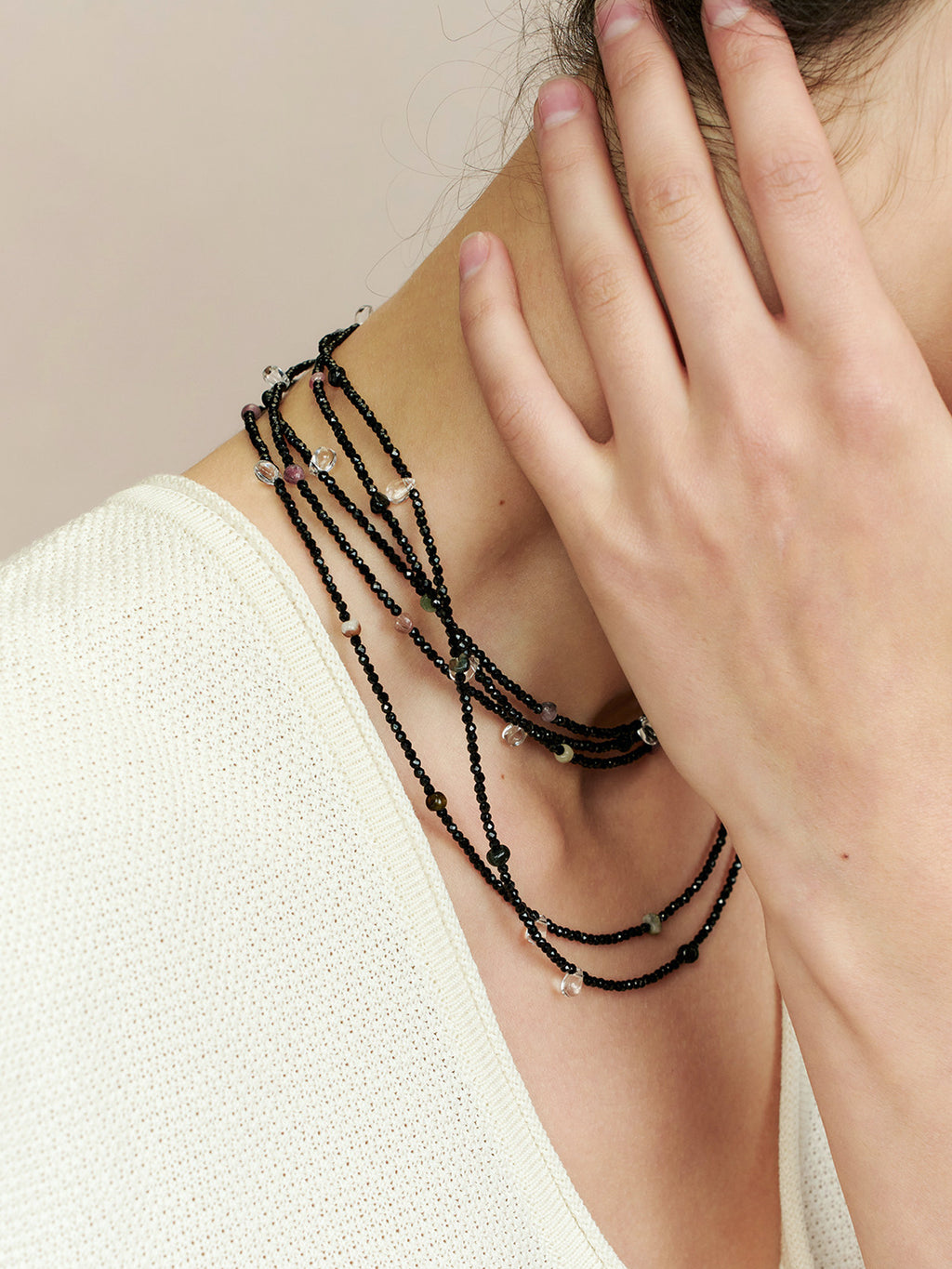Close-up of a model in a white top wearing Fairyokai Starlight Chain multi-layer necklace wrapped around her neck, with her hand touching the necklace.