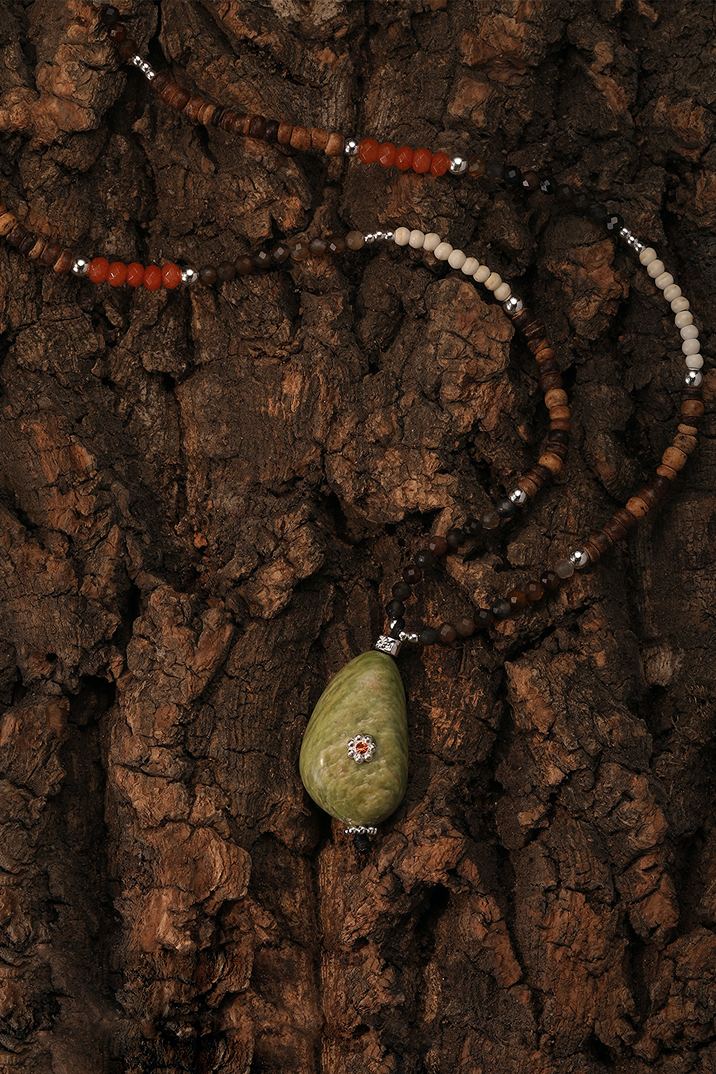 Fairyokai necklace with a green pendant on a textured brown surface