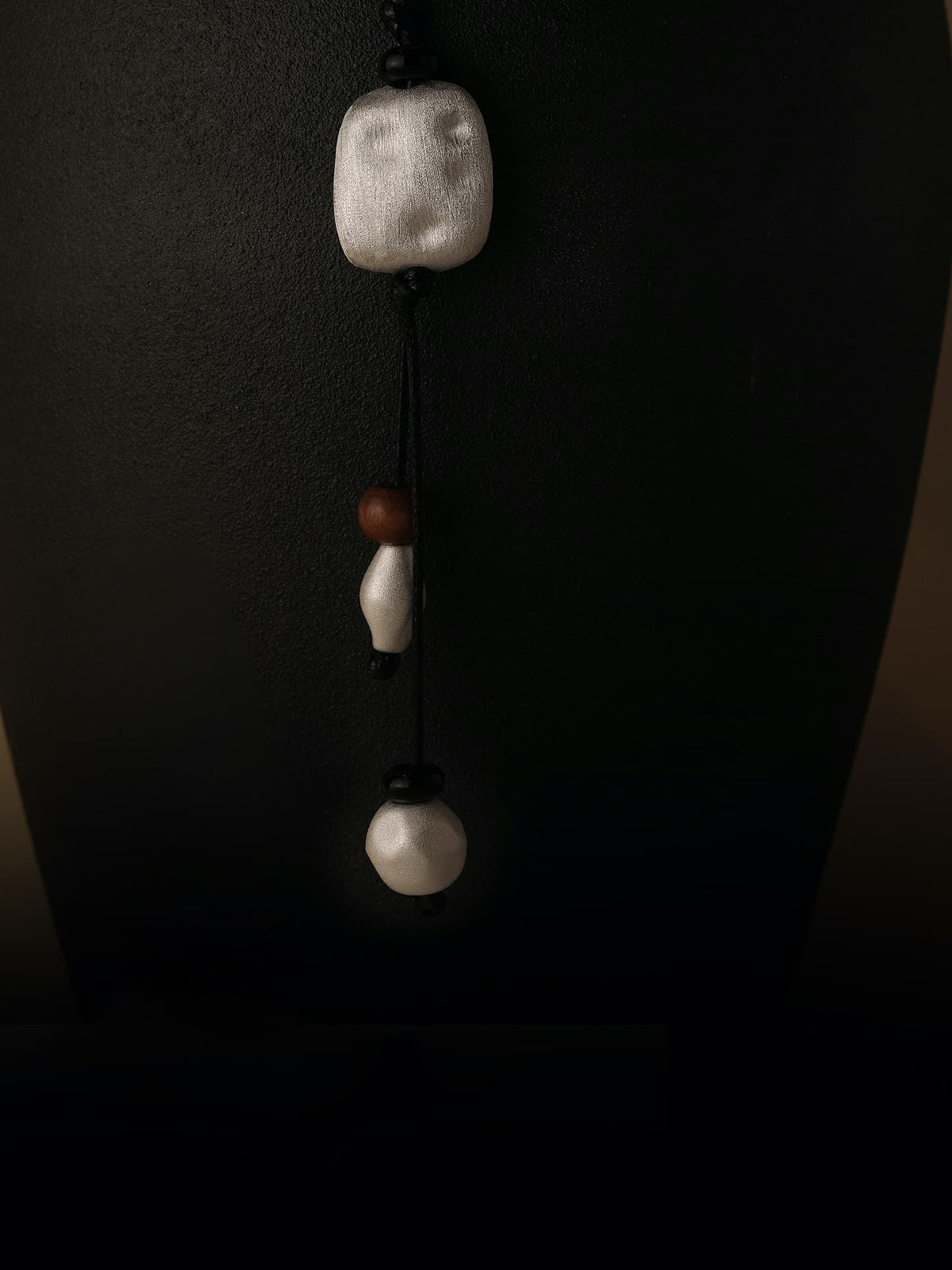 Close up of Fairyokai Suspended Wood & Waxed Cord Necklace hanging on a black display stand.