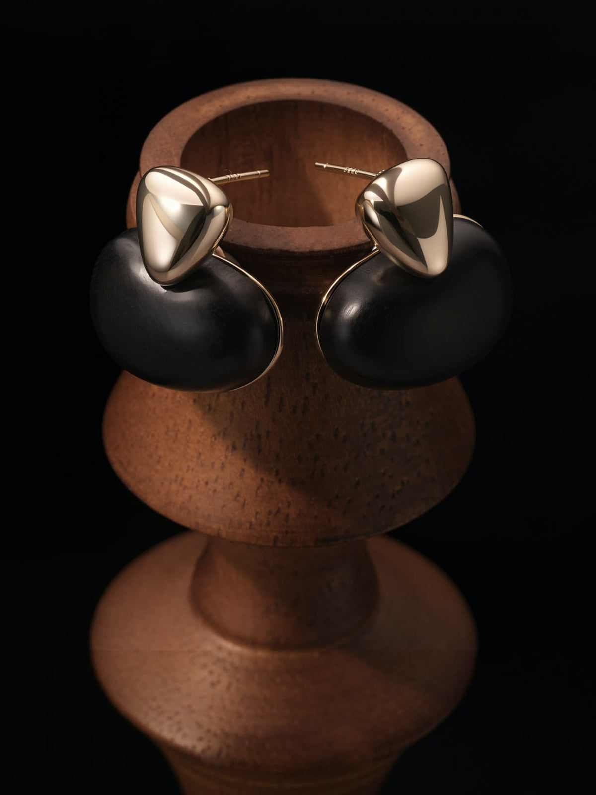 Pair of Fairyokai Tranquil Ebony Stream Stone Earrings — lifestyle shot of ebony stream stone earrings in natural setting, against a dark background