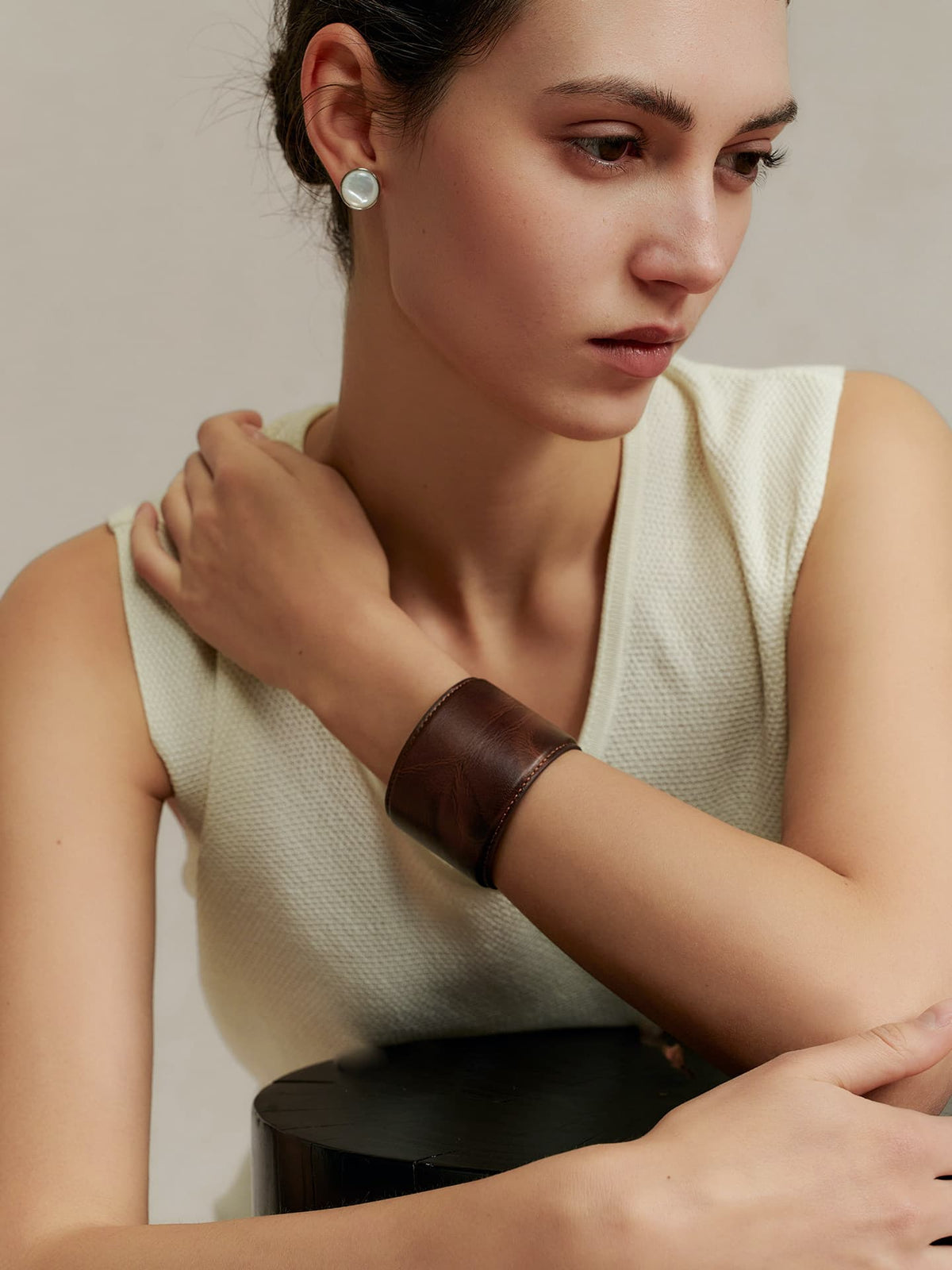 Model seated in a light top wearing the Fairyokai Vein Cuff PU leather bracelet, with the wide leather cuff wrapped around the wrist.