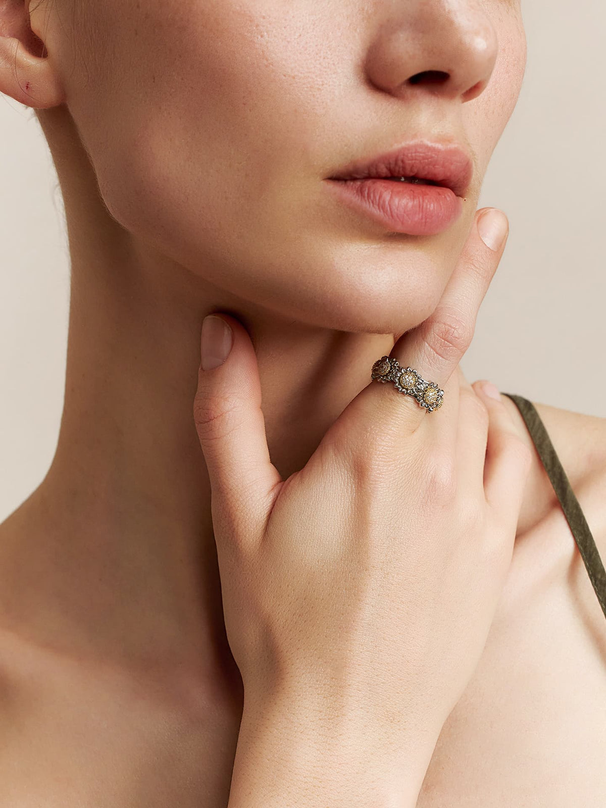 Close-up of a model wearing the Fairyokai Wild Daisy gold textured zircon ring, hand resting below the chin in a soft portrait crop.